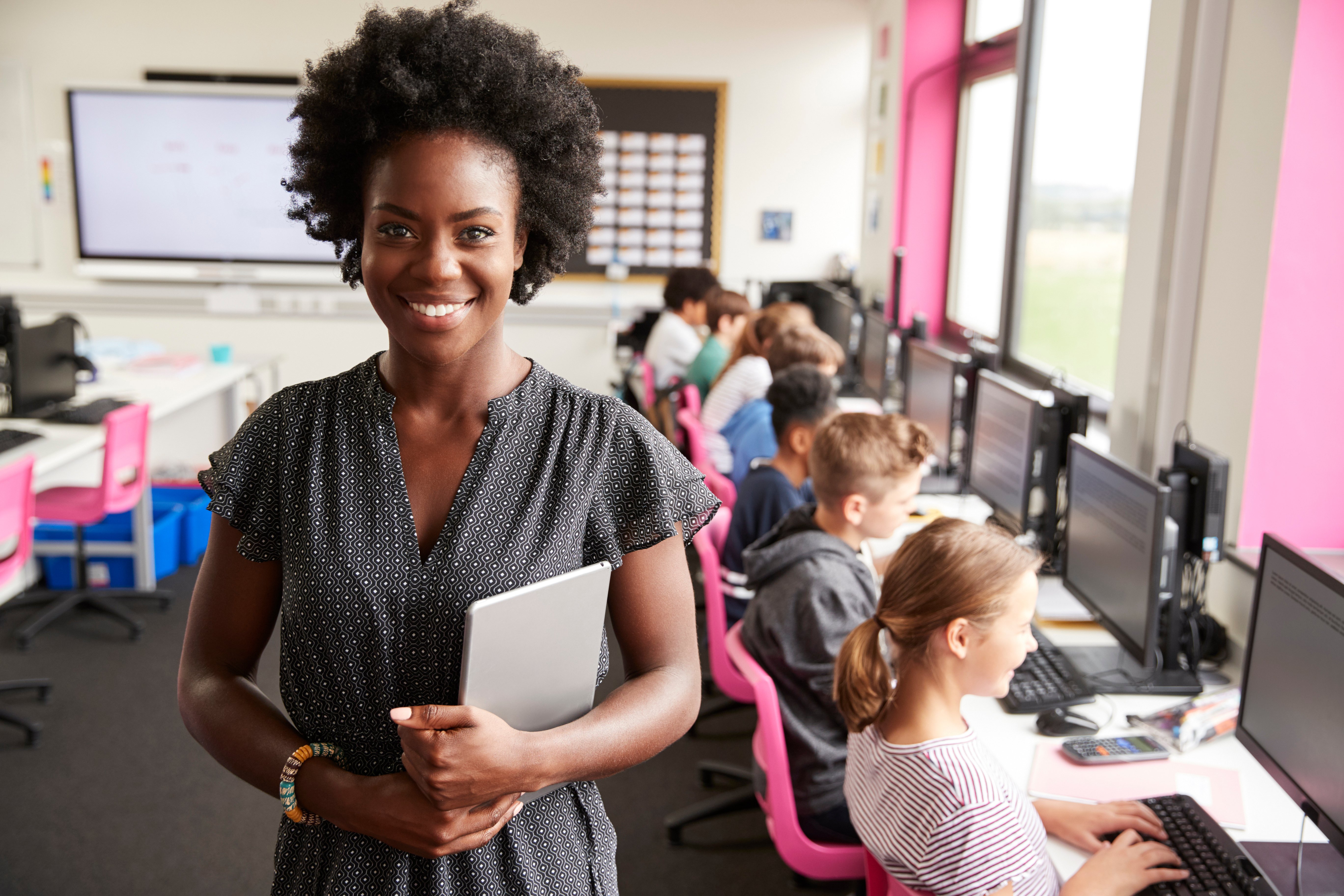 Smiling teacher with students working on computers