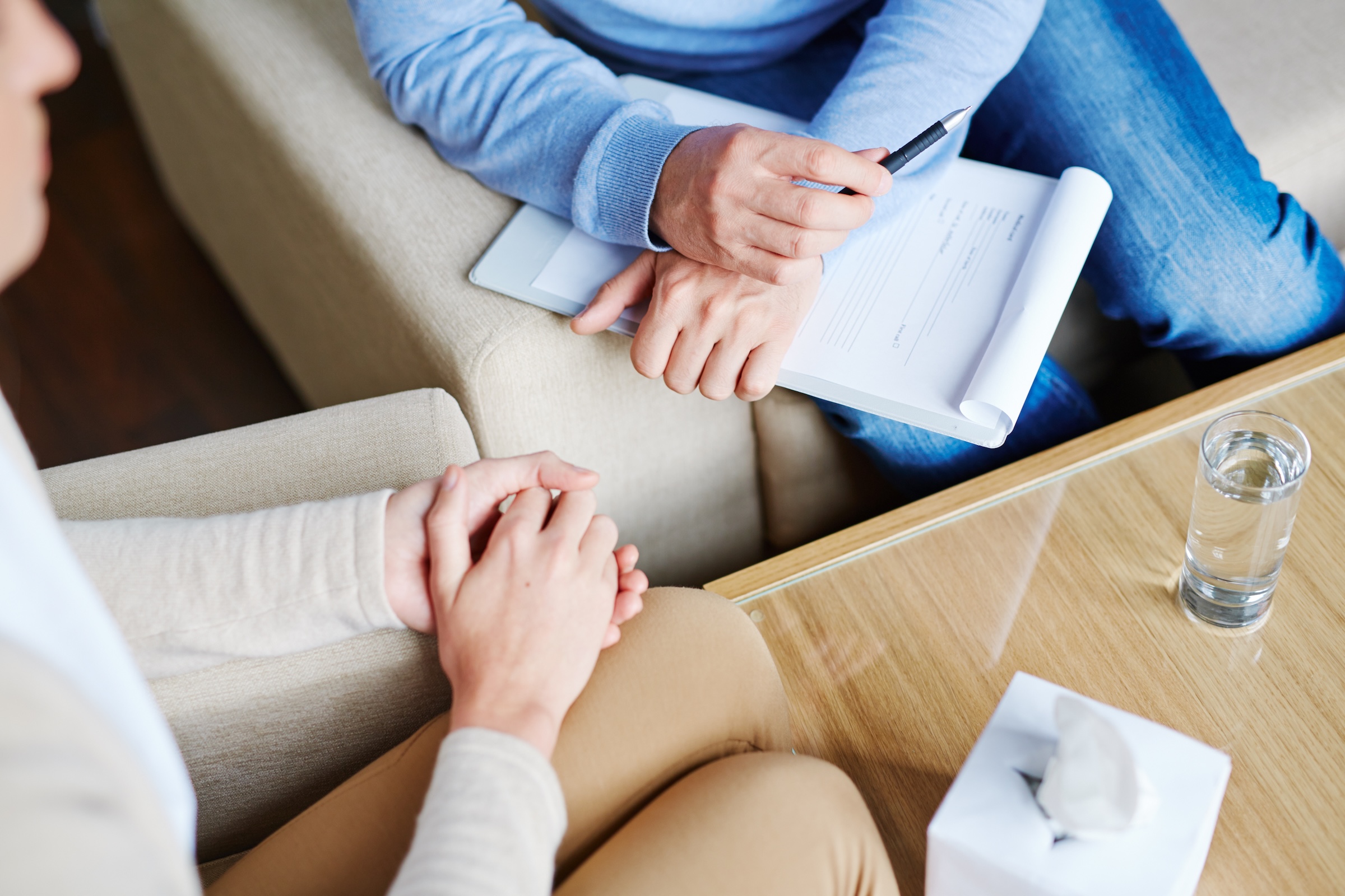 Middle-aged psychologist sitting next to his patient and listening to her childhood story in order to find reason of her disease 